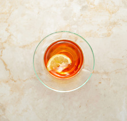 black tea with lemon in the transparent mug on a marble backgrou