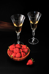 strawberries in a wooden plate and two glasses of champagne on d