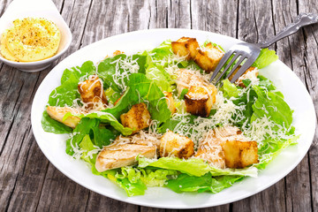 Caesar Salad with grilled chicken on a white plate, close-up