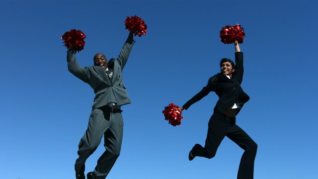 Businesspeople jumping in air with pom poms, slow motion