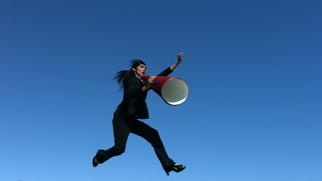 Businesswoman jumping in air with megaphone, slow motion