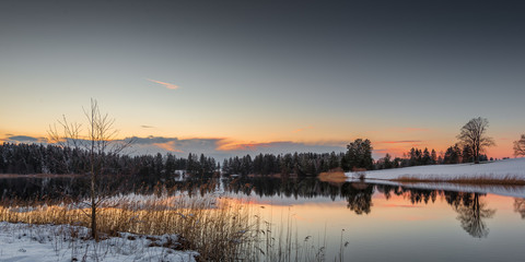 Fototapeta na wymiar small lake at winter while orange sky of sunset in bavaria