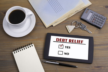 Debt Relief. Text on tablet device on a wooden table