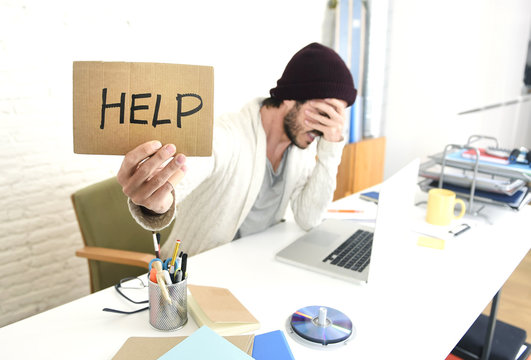 worried businessman in cool hipster beanie look holding help sign working in stress at home office