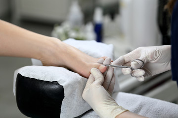 Cutting cuticle on foot, nail scissors. Pedicure process