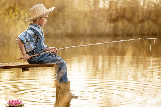 Boy fishes on a bridge on the lake