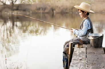 Boy fishes on a bridge on the lake