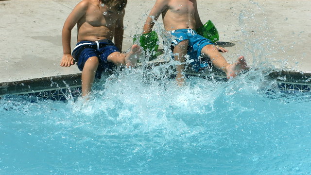 Two boys splashing feet in pool, slow motion