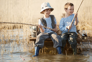 Boys fishes on a bridge on the lake