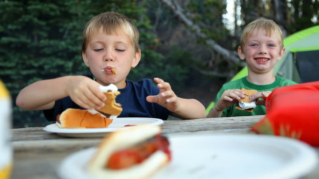 Two young boys eat smores at campground