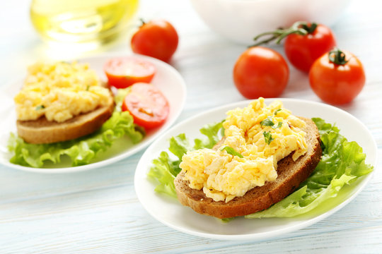 Scrambled eggs with bread and vegetables on a blue wooden table