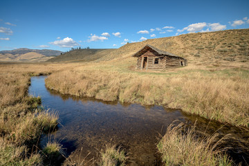 Fototapeta na wymiar Idaho log cabin falling into the earth near a stream