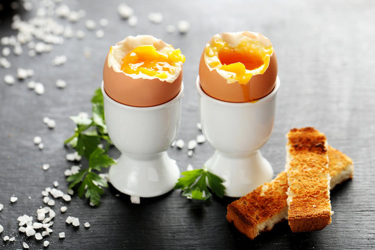 Boiled egg with toasts on a black wooden table