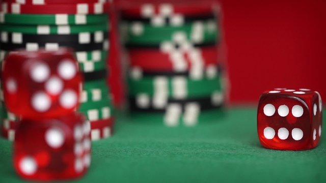 Red dice rotation and casino chips on green table