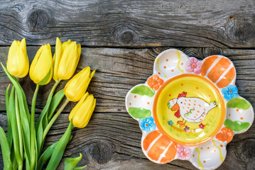 Fresh yellow tulip flowers on wooden table with ancient plates. Top view with copy space.  over wooden background.