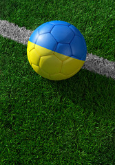 Soccer ball and national flag of Ukraine,  green grass