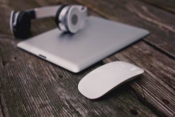 tablet with headphones and mouse on a wooden background