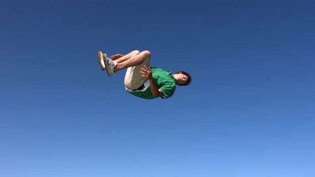 Teen boy flips in sky, slow motion