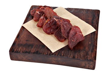 Slices of dried meat on serving dark brown board isolated.