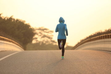 young fitness woman runner athlete running on sunrise road