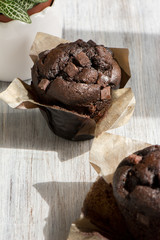 Chocolate muffins with icing and chocolate pieces.