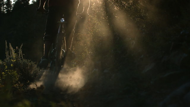 Dirt and dust flies behind mountain biker, slow motion
