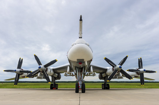 Bomber plane with propellers engines, military aircraft, air force, modern army aviation and aerospace industry, cloudy sky green grass and forest on background 