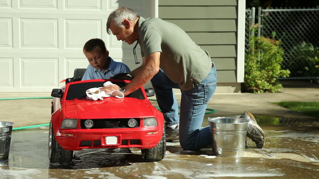 Grandfather helping grandson wash car
