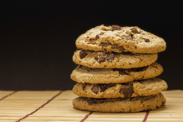 Stack of Chocolate chip cookies on wooden with black background.