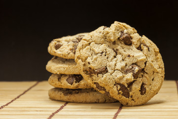 Stack of Chocolate chip cookies on wooden with black background.
