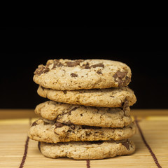 Stack of Chocolate chip cookies on wooden with black background.