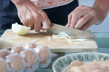 Man cuts onion on the kitchen table