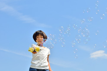 青空でシャボン玉遊びをする女の子