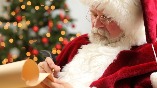 Closeup of Santa Claus writing Christmas list on scroll