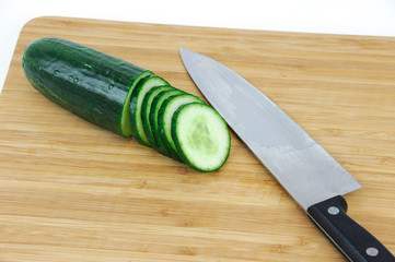 sliced cucumber on wooden board with knife