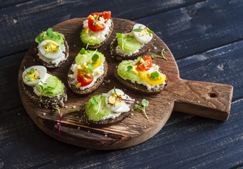 Sandwiches with soft cheese, quail eggs, cherry tomatoes and celery. Delicious healthy snack or Breakfast. On a wooden rustic board