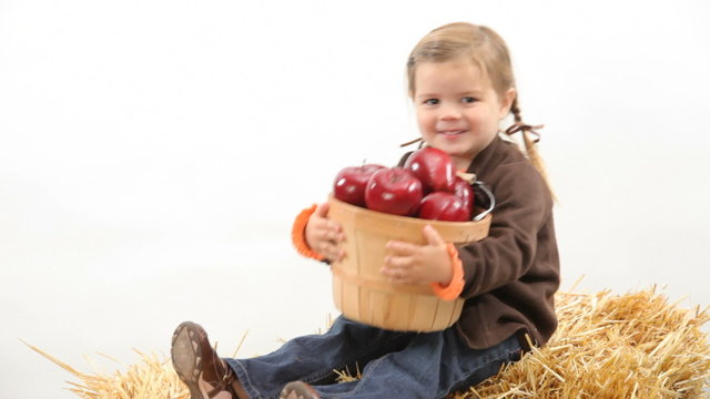 Young girl sitting with basket of apples