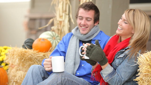 Couple in Fall sit on porch with coffee