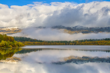 Autumn landscape with lake and mountain peaks in the background

