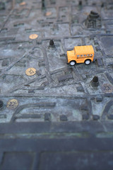 Yellow School Bus (toy model) on Ancient Metal Map for Tourists.
