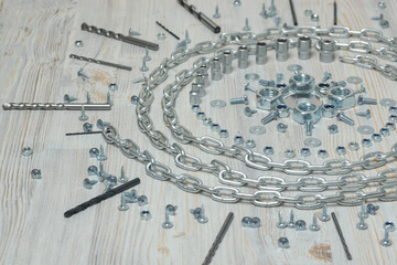 Chain, bolts and nuts on white wooden bench in the form of mandala