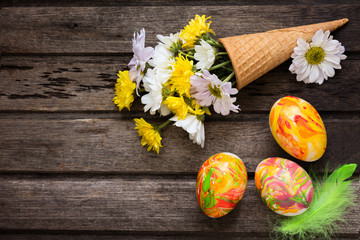 Easter background with eggs, flowers, and decoration on wooden b