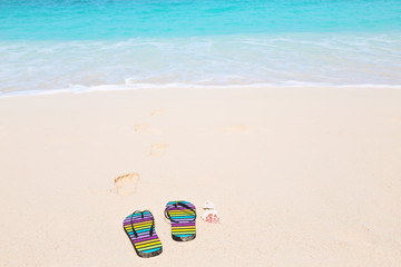 Multicolored flip-flops on a sunny beach..Tropical beach vacatio