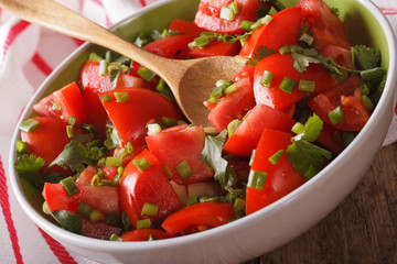 Homemade fresh tomato salad with herbs close up in a bowl. Horizontal
