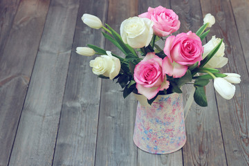 Bouquet with roses and tulips in a jug.