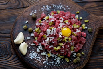 Beef steak tartare on a rustic wooden serving board, close-up