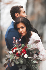 Gorgeous wedding couple kissing and hugging in forest with big rocks