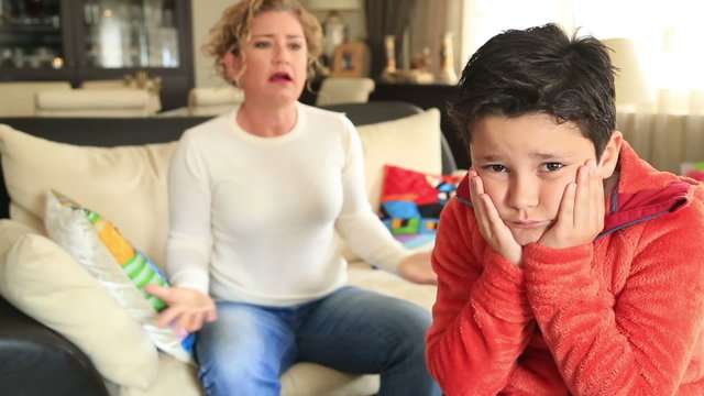 Mid adult mother scolding teenager son in living room at home