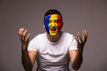 Unhappy and Failure of goal or lose game emotions of Romanian football fan in game supporting of Romania national team on grey background. European football fans concept.