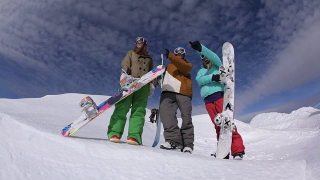 Three snowboarders look out from mountain top